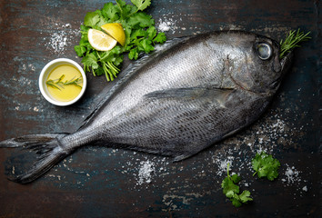 Raw dorado fish with spices cooking on grill board Top view