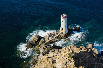 View from above, stunning aerial view of an old and beautiful lighthouse located on a rocky coast...