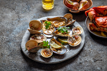 Raw seafood, crabs, clams and mussels shellfish with lemon and cilantro on gray plate