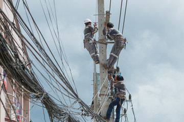 Electricians repairing,electricians repairing wire on electric power pole, power linesman climb the pole.It's a dangerous job.