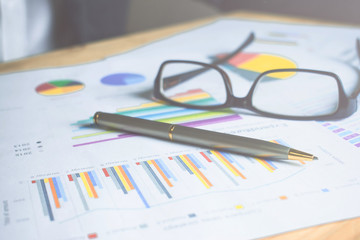 Fototapeta premium Business desk with pen, eyeglass and document. Close up.
