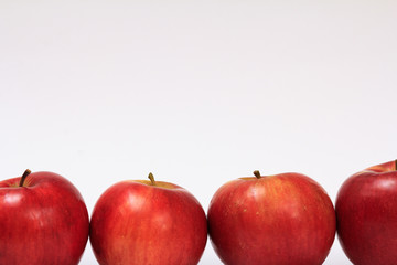Row of ripe apples on a white background.