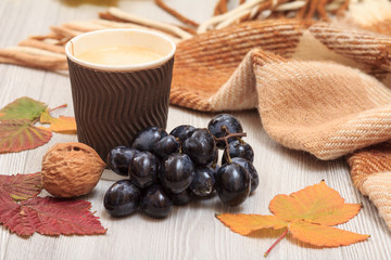 Cup of coffee, grapes, walnuts and dry leaves in an autumn still llife.