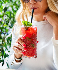woman drinking summer cocktail with strawberries and mint