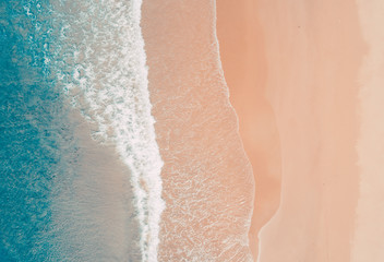 Aerial view to tropical sandy beach and blue ocean. Top view of ocean waves reaching shore on sunny...