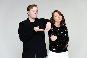 Portrait below the belt on a white background pretty young brunette woman in a black sweater and a young man in a black shirt. Standing in different poses, talking, showing emotions.
