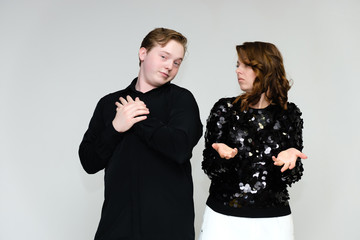 Portrait below the belt on a white background pretty young brunette woman in a black sweater and a young man in a black shirt. Standing in different poses, talking, showing emotions.