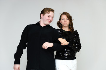 Portrait below the belt on a white background pretty young brunette woman in a black sweater and a young man in a black shirt. Standing in different poses, talking, showing emotions.