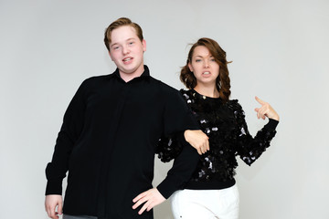 Portrait below the belt on a white background pretty young brunette woman in a black sweater and a young man in a black shirt. Standing in different poses, talking, showing emotions.