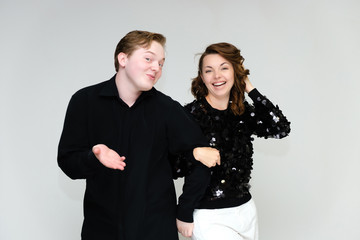 Portrait below the belt on a white background pretty young brunette woman in a black sweater and a young man in a black shirt. Standing in different poses, talking, showing emotions.