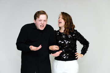 Portrait below the belt on a white background pretty young brunette woman in a black sweater and a young man in a black shirt. Standing in different poses, talking, showing emotions.