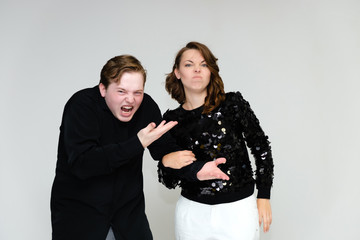 Portrait below the belt on a white background pretty young brunette woman in a black sweater and a young man in a black shirt. Standing in different poses, talking, showing emotions.