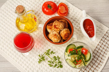 Fried meat cutlets in bowl, salad, glass of wine and bottle with sunflower oil