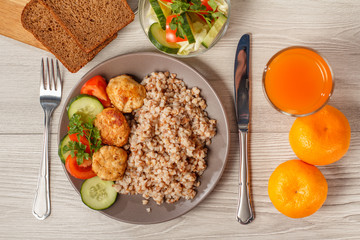 Plate with buckwheat, fried meat cutlets and pieces of fresh cucumber and tomato
