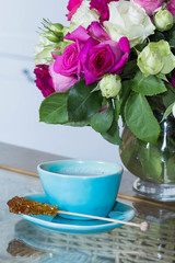 blue ceramic cup with coffee and roses blowers on glass table