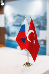 Russian and Turkish flags on metal stand on business conference or exhibition, international relations, trade, cooperation concept