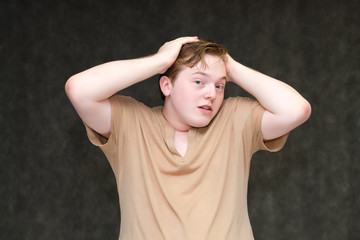 Portrait to the waist on a gray background of a handsome young man in a brown T-shirt. stands directly in front of the camera in various poses, talking, demonstrating emotions.