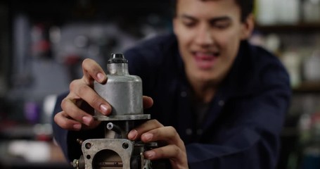 4K Cheerful young mechanic in garage workshop learning to rebuild vehicle engine