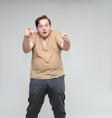 Portrait of a knee on a white background cute young man in a brown T-shirt in jeans. Standing right in front of the camera in various poses, talking, demonstrating emotions.