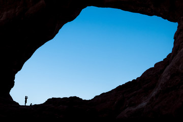 Tourist man taking a picture in one of "the windows" - Arches National Park, Utah