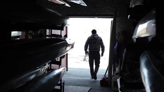 canoe and kayak. A man leaves the warehouse from darkness into the light.