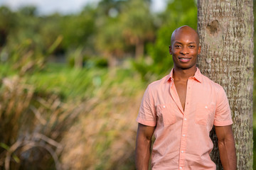 Handsome African American male model posing in a pink button shirt. Male model showing chest under buttons