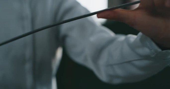 Cinematic slow motion close up a fence with professional equipment is controlling a rapier before to start a practising assaults of fencing in a gym.