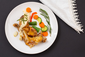 Rabbit legs baked in white wine with bechamel sauce on a ceramic plate.