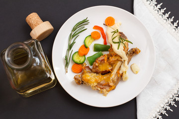 Rabbit legs baked in white wine with bechamel sauce on a ceramic plate.