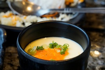 Blurred image of Steamed egg with scallion sliced in big bowl on able in restaurant ready to eat, Kai thoon is Thai traditional (Chawanmushi), Clean food of healthy concept, on dark background