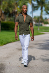 Photo of a man approaching walking towards the camera outdoors in a park scene summertime