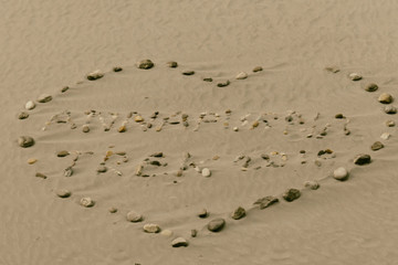 River stones formation, in the shape of heart with a sign ANNAPURNA TREK 2018 inside the heart. All placed on the sandy riverbank. Annapurna Circuit Trek, Himalayas, Nepal.