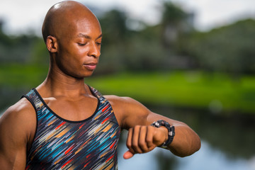 Portrait of a African American fitness model looking at his smartwatch