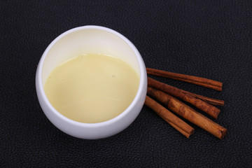 Condenced milk in the bowl with sinnamon and pastry