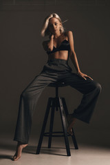 Stylish fashion trendy blonde girl with elegant hairstyle in classic trousers and black lingerie...