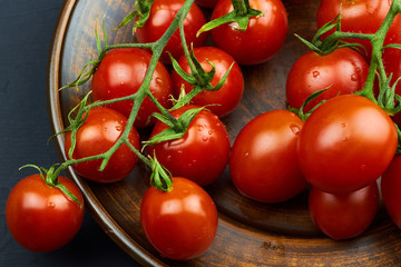 Close-up view of juicy red ripe tomatoes on a brown plate at a dark background