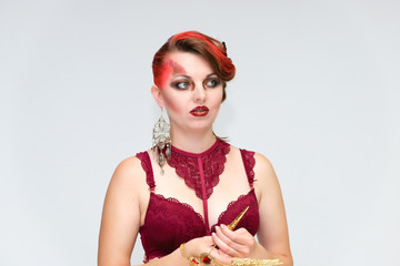 Portrait to the waist on a white background of a pretty young brunette woman with beautiful makeup, with gold jewelry on her hand. Beauty, great makeup. Shows emotions.