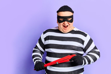 cunning fat cruel man going to do criminal illegal act, isolated blue background. studio shot.