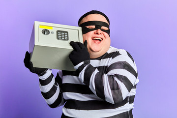 happy positive fat burglar is satisfied with a good day of crime. prisoner in striped uniform is...