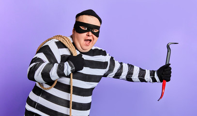 funny fat man comitting a crime, isolated blue background. studio shot.close up portrait