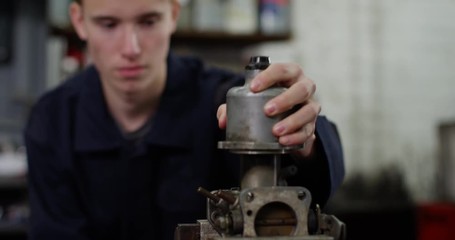 4K Young mechanic in garage workshop learning to rebuild vehicle engine