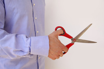 businessman in a blue shirt holds in his hand open large stationery scissors