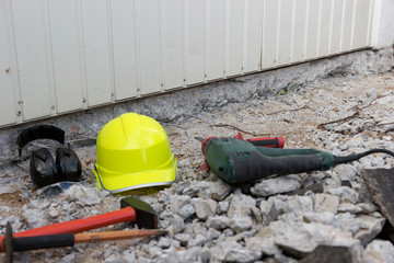 Electric hammer helmet and hearing protection lying on the rubble. Occupational safety at the construction site