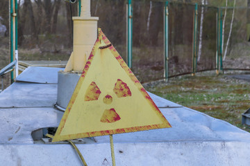 Radioactivity sign. Black triangle with a fan in the middle on the yellow background. The sign is really rusty and weary. Located in a contaminated area of Chernobyl, Ukraine.