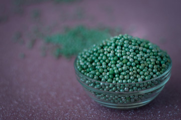 Green ball crystal sugar sprinkle dots, on glitter pink background, decoration for confectionery.  Sugar, sweetness, diabetes concept.