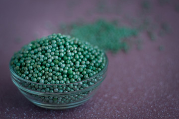 Green ball crystal sugar sprinkle dots, on glitter pink background, decoration for confectionery.  Sugar, sweetness, diabetes concept.
