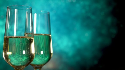 Two glasses of champagne with bubbles on blue background.