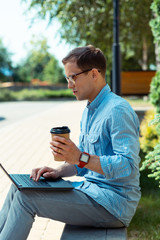 Businessman enjoying coffee break outside and reading e-mails