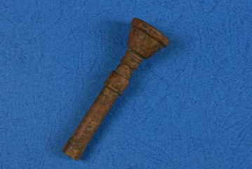 one brown old bronze mouthpiece lies on a blue table