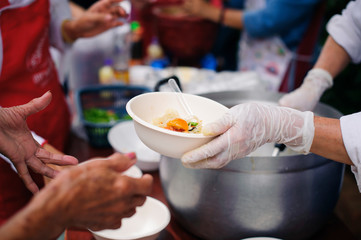 Hands of beggars accepting food from the hands of volunteers who come to help free food breaks :...